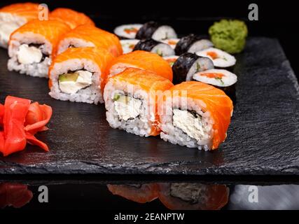 Due diversi tipi di sushi roll su una tavola di pietra. Cucina giapponese. Foto Stock