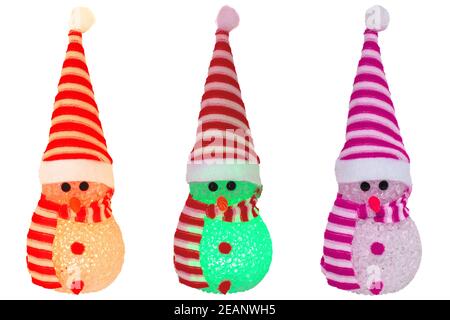 Elementi decorativi di Natale isolati. Primo piano di tre simpatici snowman invernali illuminati di vari colori con cappello a righe rosso bianco e sciarpa isolati su uno sfondo bianco. Fotografia macro. Foto Stock