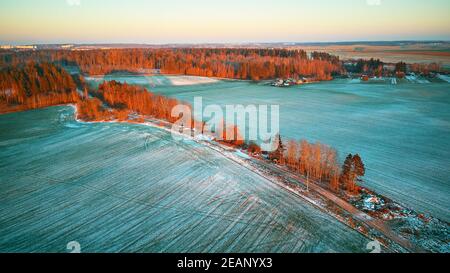 Alberi colorati dicembre tramonto scena aerea. Strada sterrata rurale. Vista dall'alto sulla campagna. Foto Stock