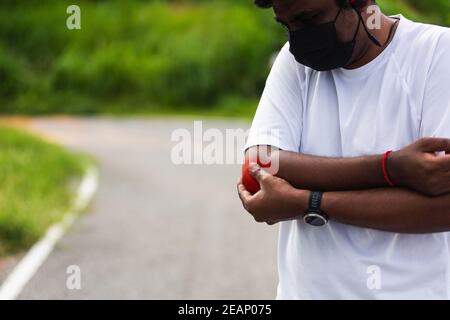 sport corridore uomo nero indossare orologio che ha gomito dolore Foto Stock