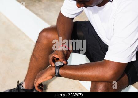 il corridore sportivo uomo nero indossa orologio moderno intelligente he tempo seduta riposante Foto Stock