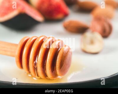 cucchiaia di miele e gocce di miele sul piatto primo piano Foto Stock