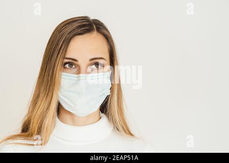 Donna ansiosa con maschera facciale preoccupata per l'epidemia di Covid-19 Foto Stock