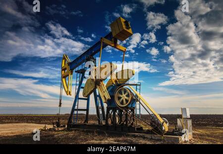 Olio in funzione ben profilato su cielo nuvoloso drammatico Foto Stock