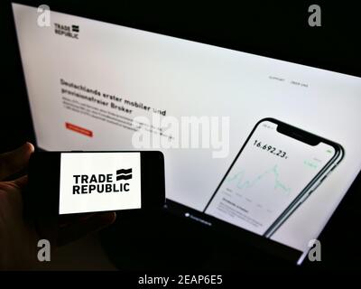 Persona in possesso di smartphone con logo del broker online tedesco Trade Republic Bank GmbH sullo schermo di fronte al sito web. Mettere a fuoco il display del telefono. Foto Stock