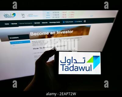 Persona che tiene il telefono mobile con il logo di affari della borsa Saudita Tadawul sullo schermo davanti alla pagina web. Focus sul display del cellulare. Foto Stock