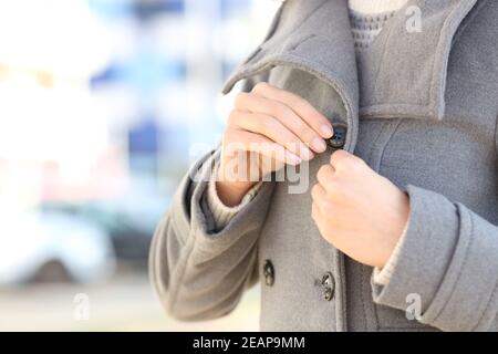 Donna mani che allacciano il bottone di giacca in inverno nel via Foto Stock