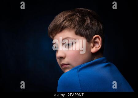 primo piano vista laterale ritratto di un ragazzo bianco europeo adolescente con capelli castani chiari, che indossa una t-shirt sportiva blu, su sfondo isolato Foto Stock