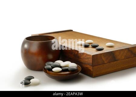 pietre bianche e nere di gioco di baduk su tavola di legno isolato su bianco Foto Stock