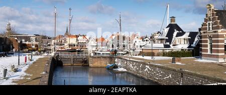 Paesaggio urbano di Lemmer, Paesi Bassi, porto in inverno con neve in Friesland con una serratura quasi vuota di fronte con una barca ghiacciata. Widescreen Foto Stock