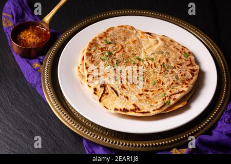 Concetto di cibo punto fuoco fatto in casa Paratha, Parotta o Porotta strato pane piatto su sfondo nero con spazio di copia Foto Stock