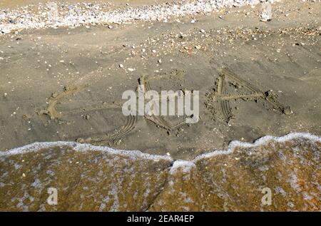 L'iscrizione del mare sulla sabbia. Sabbia costiera e onde. Iscrizioni su Riva Foto Stock