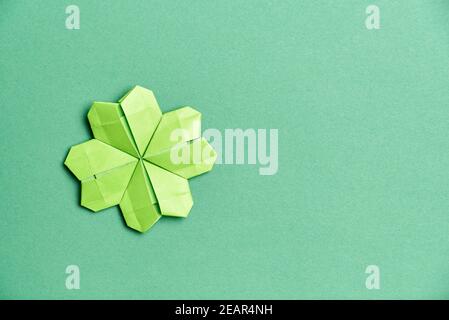 shamrock a quattro foglie Origami, in carta verde chiaro, su sfondo verde. Concetti di fortuna e giorno di San Patrizio. Immagine con spazio di copia. Foto Stock