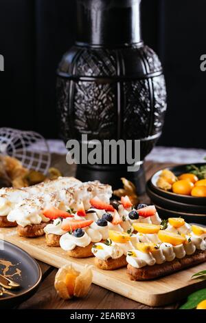 Deliziosi eclair appena sfornati con frutti di bosco su un'oliva di legno scheda Foto Stock