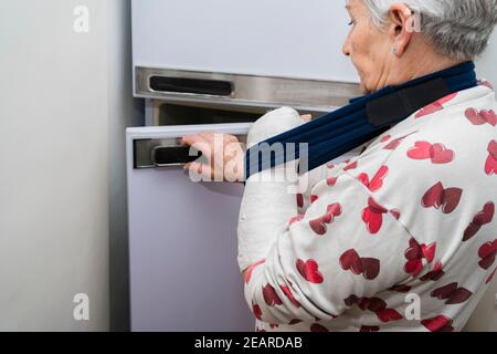 Donna anziana caucasica dai capelli bianchi con braccio rotto con bianco bendaggio Foto Stock