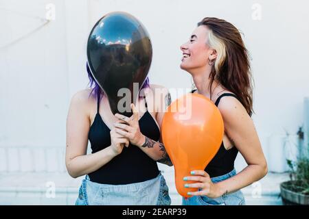 Due amiche si divertono con palloncini colorati. Sfondo bianco non isolato Foto Stock