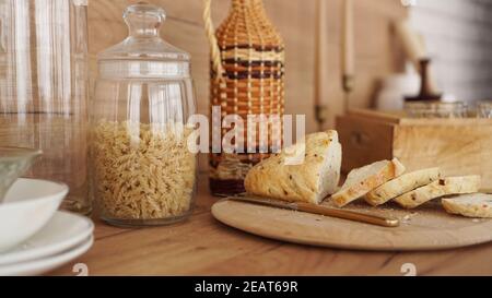 Pane bianco affettato su un vassoio di legno moderna cucina in stile scandinavo. Pasta in un vaso di vetro Foto Stock