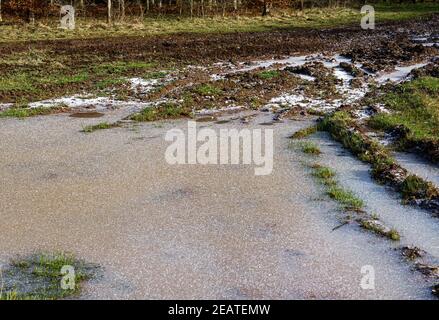 Neve coperta ghiacciata puddle fuori di una pista del carro armato su Salisbury Plain, Wiltshire Foto Stock