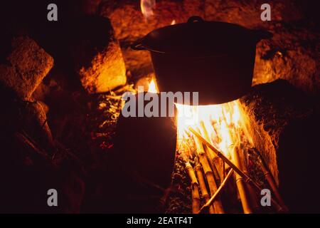 Pentola di ferro che cucinano sopra il fuoco di bambù alla notte Foto Stock