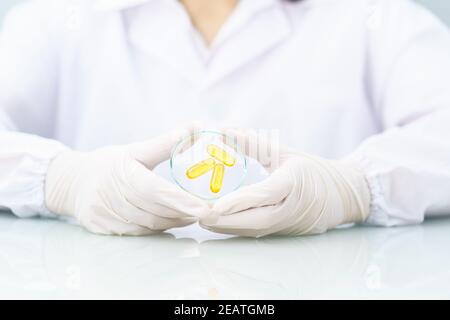 Scienziato che tiene la capsula di Omega 3 in camice da laboratorio Foto Stock