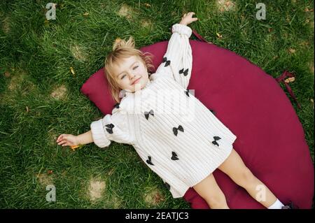 Bambina sdraiata sull'erba del giardino Foto Stock