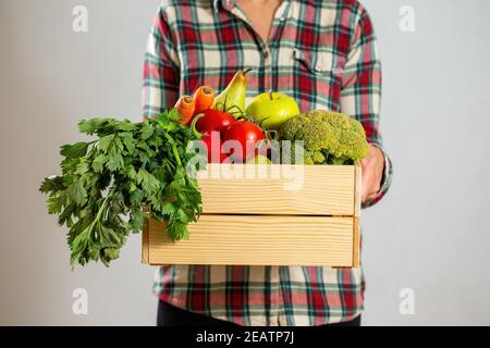 Donna in flanella camicia contenitore con frutta fresca e. verdure Foto Stock