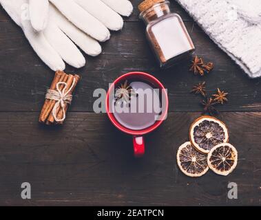 mittens lavorato a maglia e tazza rossa con una bevanda su a. tavolo di legno marrone Foto Stock