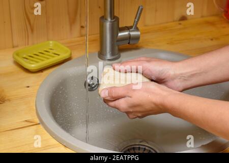 Le mani della ragazza che si inzuppano le mani con sapone in cucina lavello Foto Stock