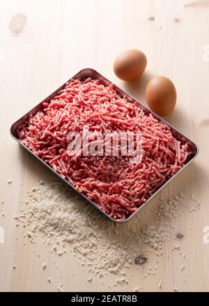 Carne macinata e uova in un vassoio su un legno sfondo Foto Stock