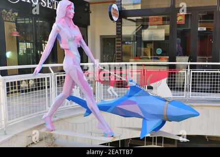 Scultura colorata al centro commerciale -giovane donna che cammina uno squalo- Foto Stock