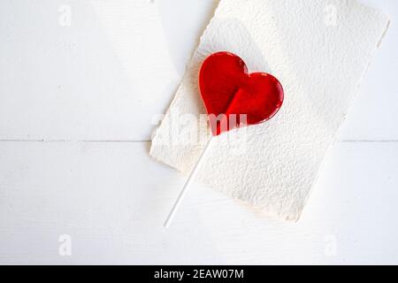 Concetto di amore. San Valentino. Cuore rosso lollipop su sfondo bianco tavolo. Foto Stock