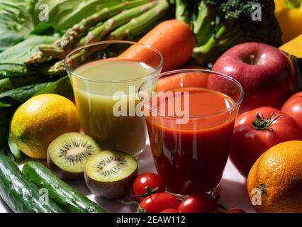 Un sacco di frutta e verdura su uno sfondo bianco con un bicchiere di frullato verde e succo di verdure Foto Stock