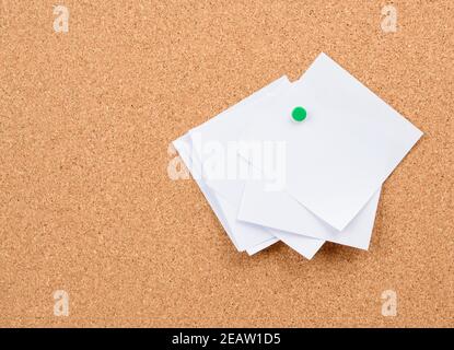 pezzi bianchi squadrati di carta incappati su un sughero scheda Foto Stock