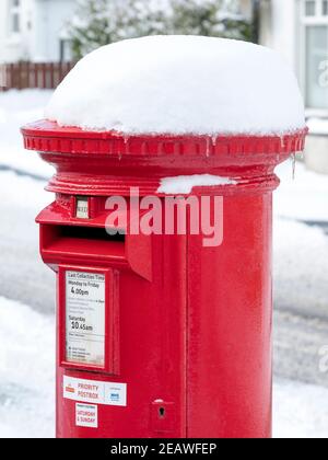 Neve coperta rosso priorità postbox Stoneyburn villaggio, Lothian occidentale. Foto Stock