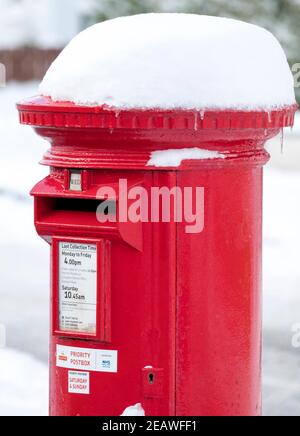 Neve coperta rosso priorità postbox Stoneyburn villaggio, Lothian occidentale. Foto Stock