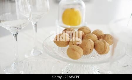 Svuotare i bicchieri da vino e le noci su un piatto di vetro sfondo sfocato degli interni moderni Foto Stock