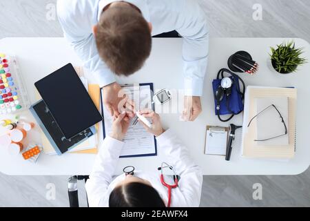 Medico che prende l'esame del sangue dal dito dei pazienti con la parte superiore della lancetta visualizza Foto Stock