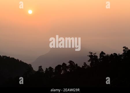 Colline himalayane dalle silhouette all'alba, a sud della catena montuosa dell'Annapurna. Nepal. Foto Stock