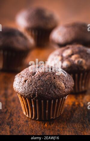 Muffin al cioccolato. Dolci cupcake scuri su tavolo di legno. Foto Stock