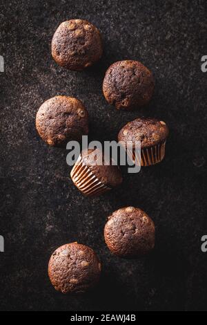 Muffin al cioccolato. Dolci cupcake scuri su tavolo nero. Vista dall'alto. Foto Stock