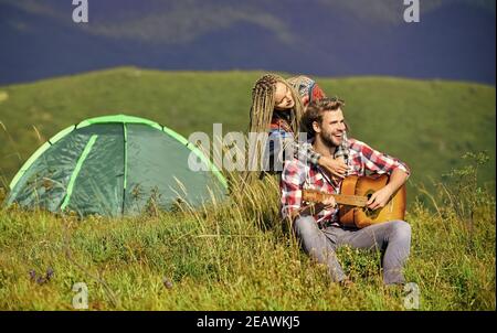 Aria fresca e sensazioni pure. Coppia in amore felice rilassante sfondo natura. Fidanzata chitarra vicino tenda campeggio. Vacanze estive. Vacanza in campeggio. Escursioni romanticismo. Campeggio in montagna. Foto Stock