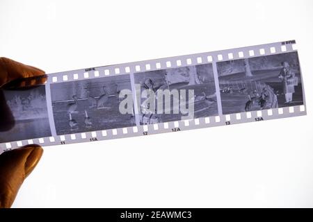 Una mano che tiene una striscia di negativi di pellicola in bianco e nero da 35 mm Foto Stock
