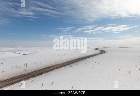 Vista aerea invernale della ghiaia Inuvik-Tuktoyaktuk Highway in cima al mondo, a nord della linea degli alberi, territori del Nord-Ovest, Artico del Canada. Foto Stock