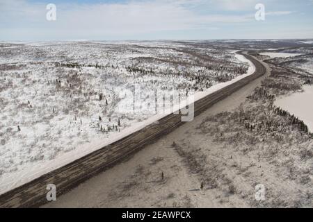 Vista aerea invernale della ghiaia Inuvik-Tuktoyaktuk Highway dall'estremità meridionale, territori nordoccidentali, l'Artico del Canada. Foto Stock