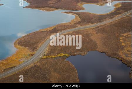 Vista aerea dall'alto dell'autostrada Inuvik-Tuktoyaktuk (costruita sopra il permafrost) con corpi idrici su entrambi i lati, territori del Nord-Ovest, artico del Canada. Foto Stock