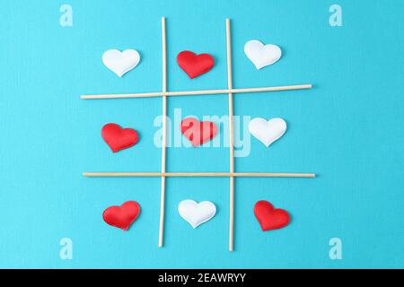 Giocare tic tac TOE con un cuore bianco e un cuore rosso su uno sfondo blu. Concetto per il giorno dell'amore, San Valentino, 14 febbraio. Carta San Valentino. Foto Stock