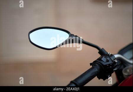 particolare di un moderno specchio retrovisore di una strada rossa moto su sfondo sfocato Foto Stock