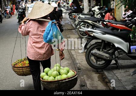 Donna venditore di strada con un cappello conico, Hanoi, Vietnam Foto Stock