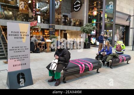 Stoccolma, Svezia. 10 Feb 2021. La gente siede sulle panchine contrassegnate con i nastri per tenere una distanza in un centro commerciale a Stoccolma, Svezia, il 10 febbraio 2021. Il numero di casi confermati di coronavirus in Svezia è stato superiore a 600,000 mercoledì, ha dichiarato l'Agenzia per la sanità pubblica del paese. Nel frattempo, il paese continua a combattere il nuovo, più contagioso ceppo COVID-19. Credit: Wei Xuechao/Xinhua/Alamy Live News Foto Stock