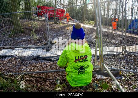 Aylesbury vale, Buckinghamshire, Regno Unito. 10 febbraio 2021. Un attivista anti HS2 guarda come un picker ciliegia arriva nei boschi. Gli ecologisti che lavorano per conto di HS2 Ltd stavano facendo indagini su pipistrelli in Jones Hill Wood oggi. Gli ecologisti stavano mettendo gli endoscopi nei roosts potenziali del bat che potrebbero avere disturbato tutti i pipistrelli di ibernazione. Si ritiene che i pipistrelli barbastelle molto rari si ruggano in questo bosco. HS2 stanno progettando di distruggere una grande parte di questo antico bosco per il controverso collegamento ferroviario ad alta velocità da Londra a Birmingham. Credit: Maureen McLean/Alamy Live News Foto Stock